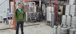 man standing in front of beer brewing equipment